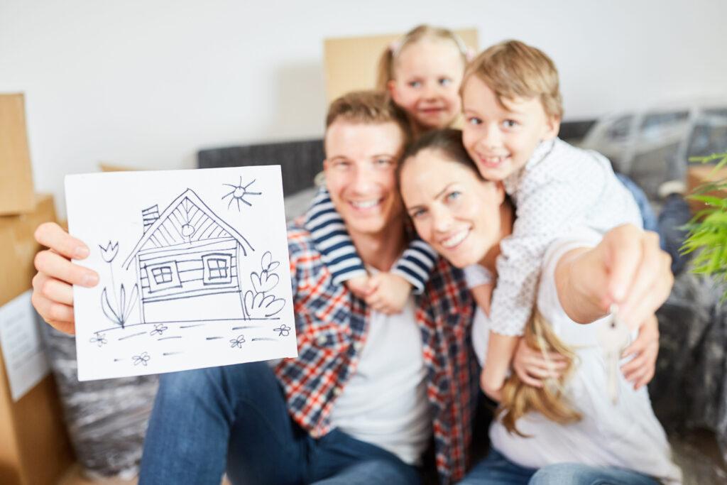 Glückliche Familie und Kinder zeigen Bild als Symbol für Eigenheim und Hauskauf