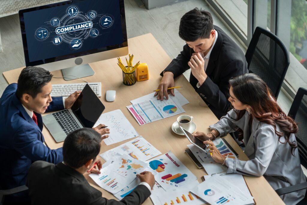 Business-Meeting zum Thema Compliance E-Learning mit digitalen Tools und Diagrammen