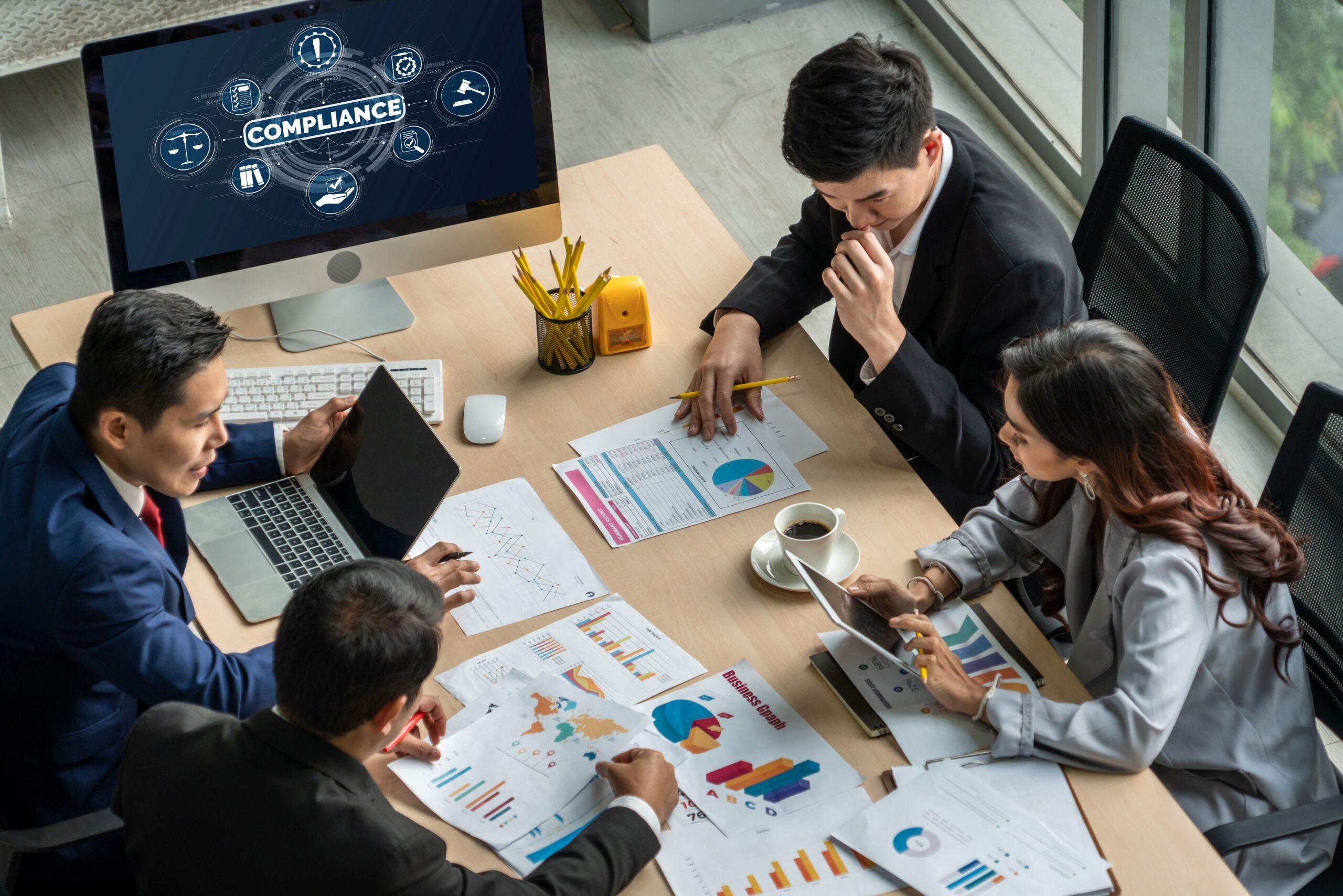 Business-Meeting zum Thema Compliance E-Learning mit digitalen Tools und Diagrammen