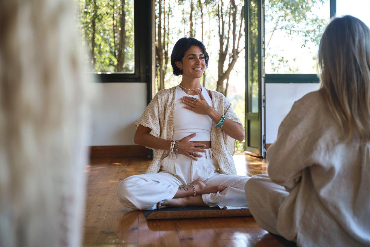 Zwei Frauen sitzen im Schneidersitz bei einer Atemuebung – bewusstes Atmen zur Stressregulation und emotionalen Staerkung durch Breathwork
