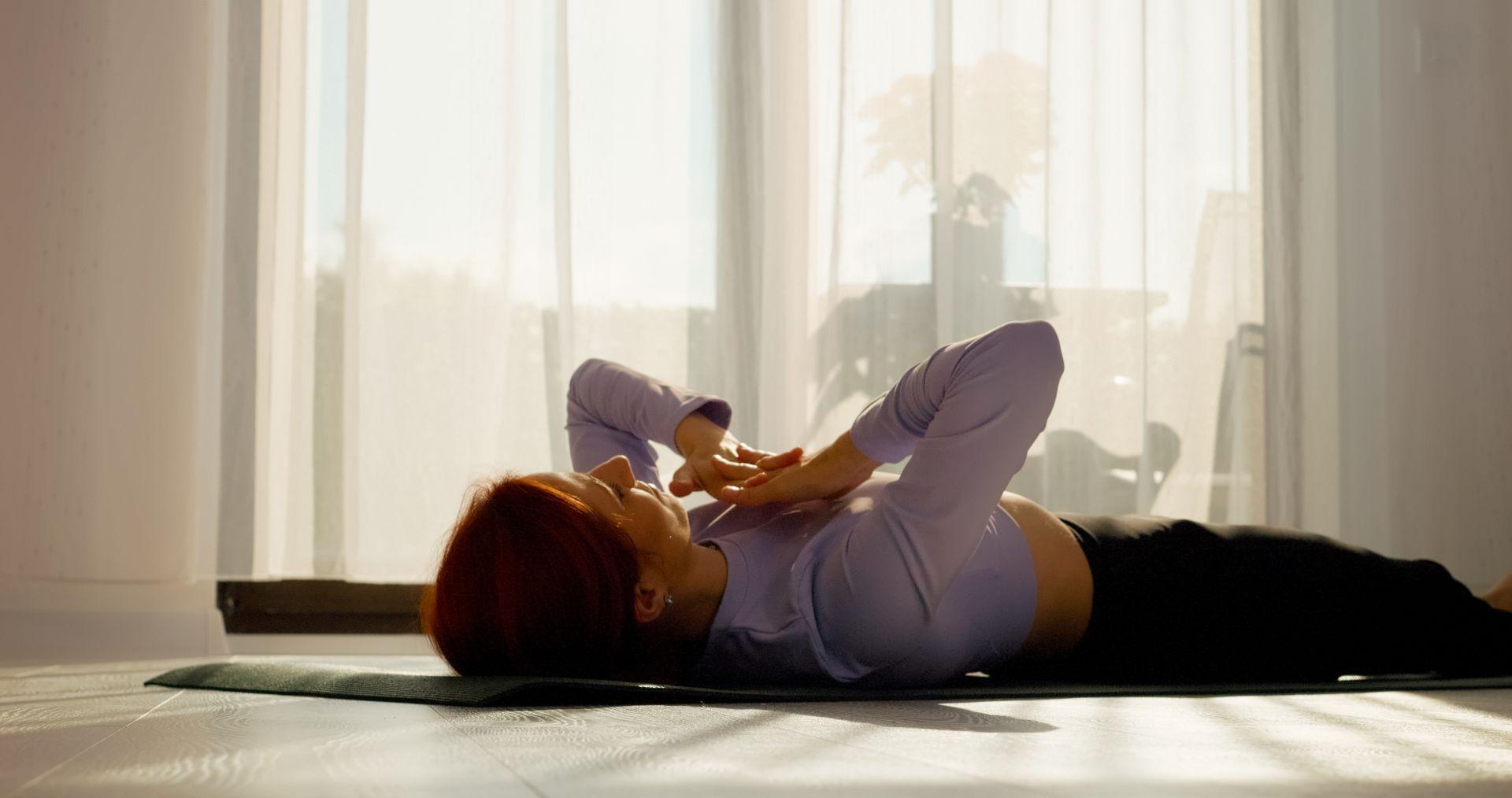Frau liegt beim Breathwork auf einer Yogamatte